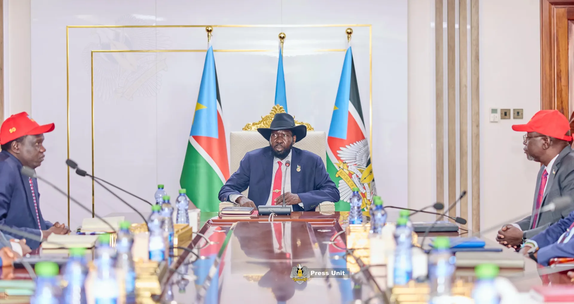The SPLM Chairman and President of the Republic at an official signing at his desk, flanked by national flags